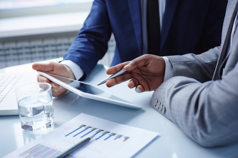 Two advisors reviewing charts and data on a tablet